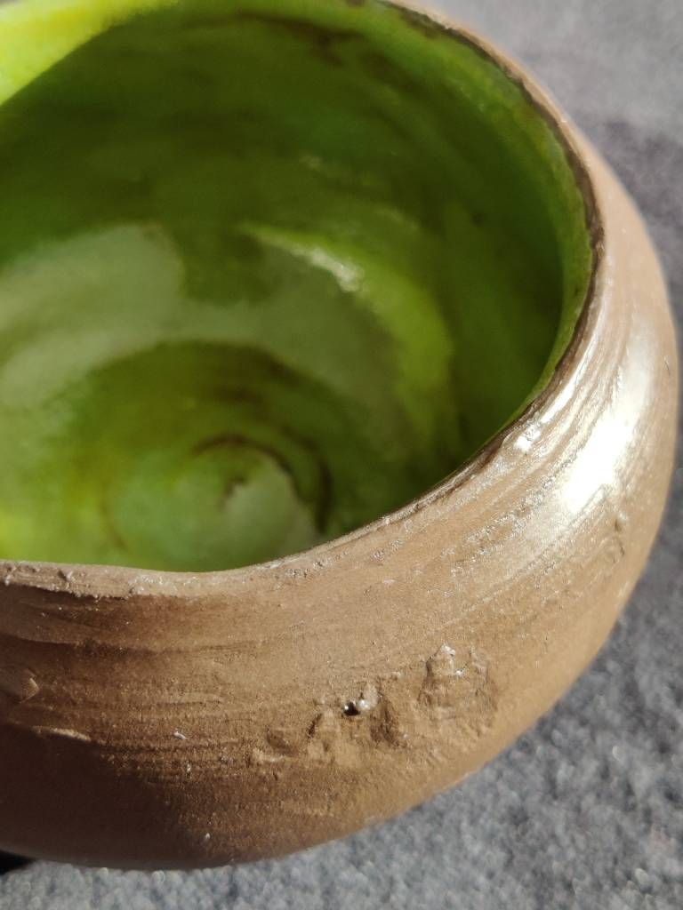 Détail de l'intérieur d'un pot en argile dont l'extérieur est laissé brut (argile marron, légèrement brillante car recouverte de cire) et intérieur vert anis.