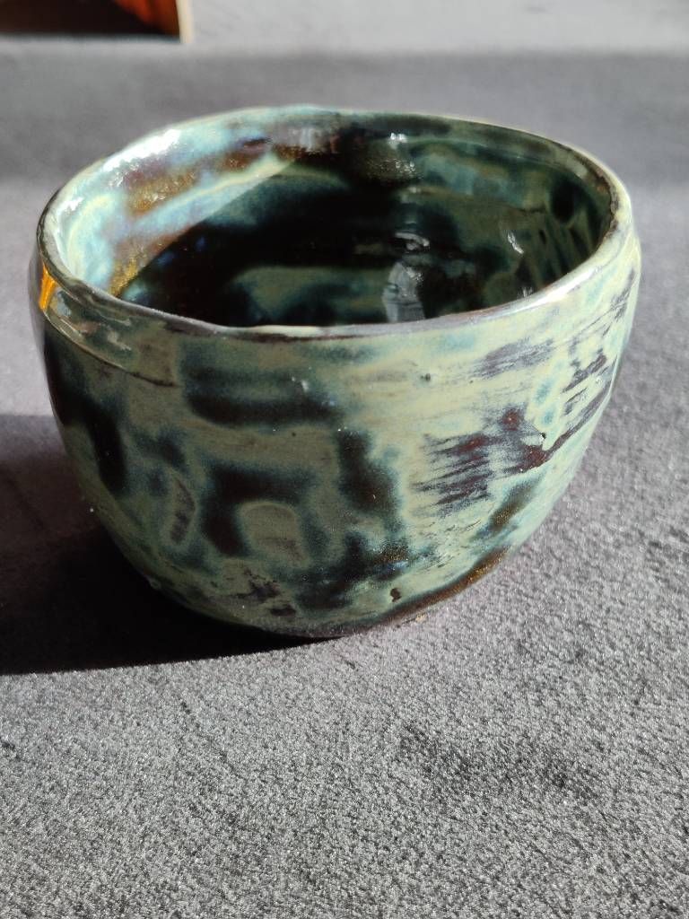 Pot en argile recouvert d'émail vert/bleu foncé/miel posé de façon très irrégulière.