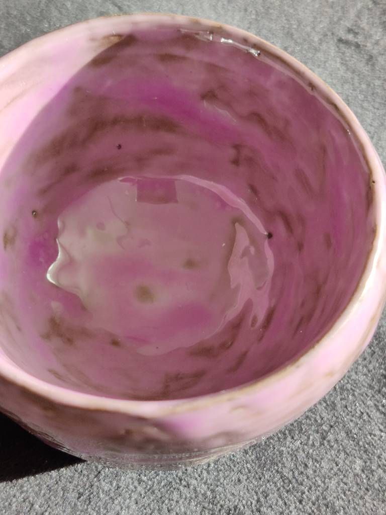 Détail de l'intérieur d'un petit pot en argile recouvert d'émail mauve posé (même s'il fait rose sur la photo) de façon très irrégulière avec des zones opaques et des traces quasi transparentes.