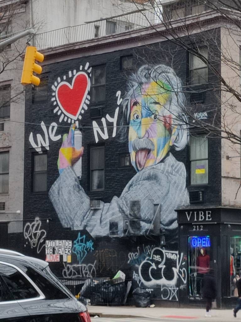 Graffiti recouvrant s'étalant sur toute la façade d'un bâtiment de deux étages représentant Albert Einstein tirant la langue tagguant "We [cœur] NY²"