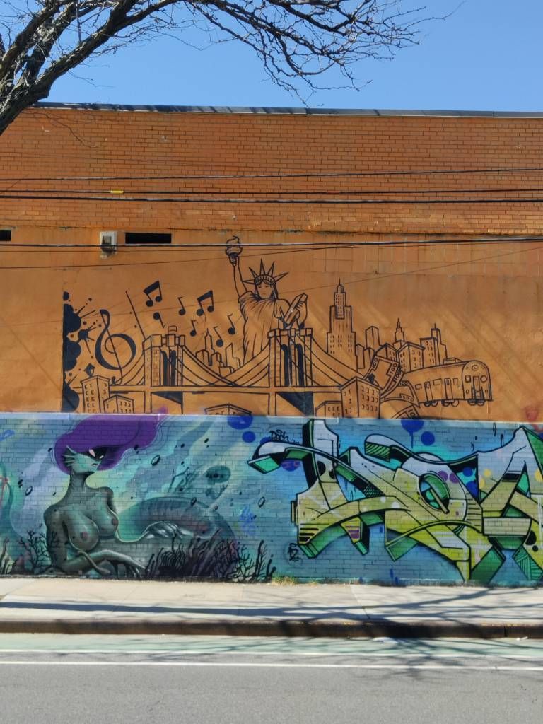 Deux murs, deux graffiti : l'un symbolisant New York (Statue de la Liberté, pont de Brooklyn, métro, buildings, musique...), l'autre représentant une sirène (plutôt version maléfique)