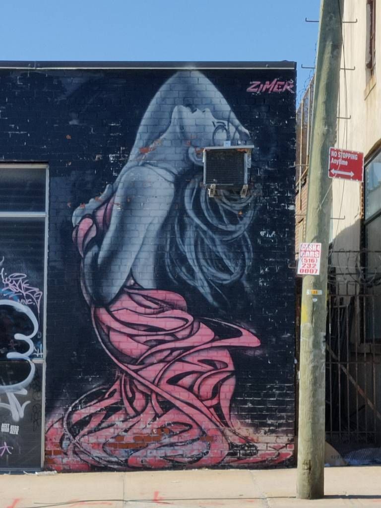 Graffiti représentant une femme se cambrant et tenant sa robe, seul élément coloré, qui reprend les codes des enchevêtrement de certaines écritures de tags