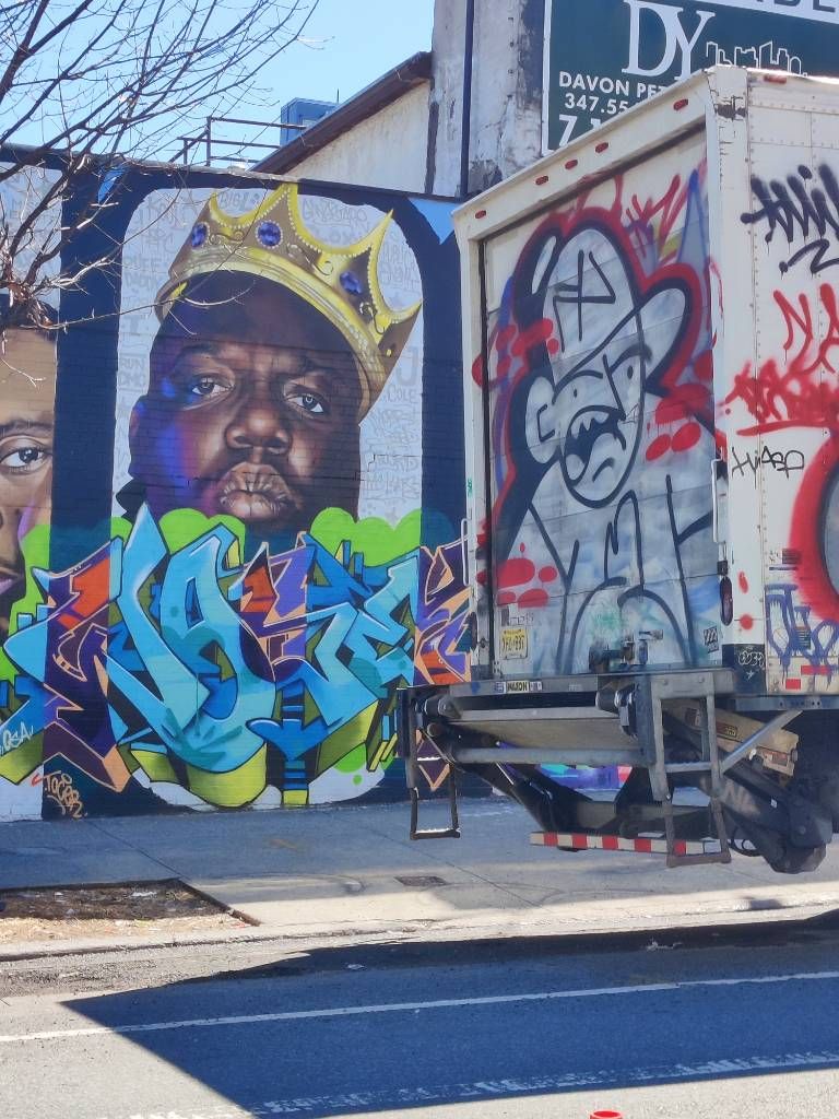 Détail d'une fresque murale représentant différentes figures du rap et du Rn'B où l'on voit The Notorious B.I.G. À l'avant plan, l'arrière d'un camion, lui aussi taggé