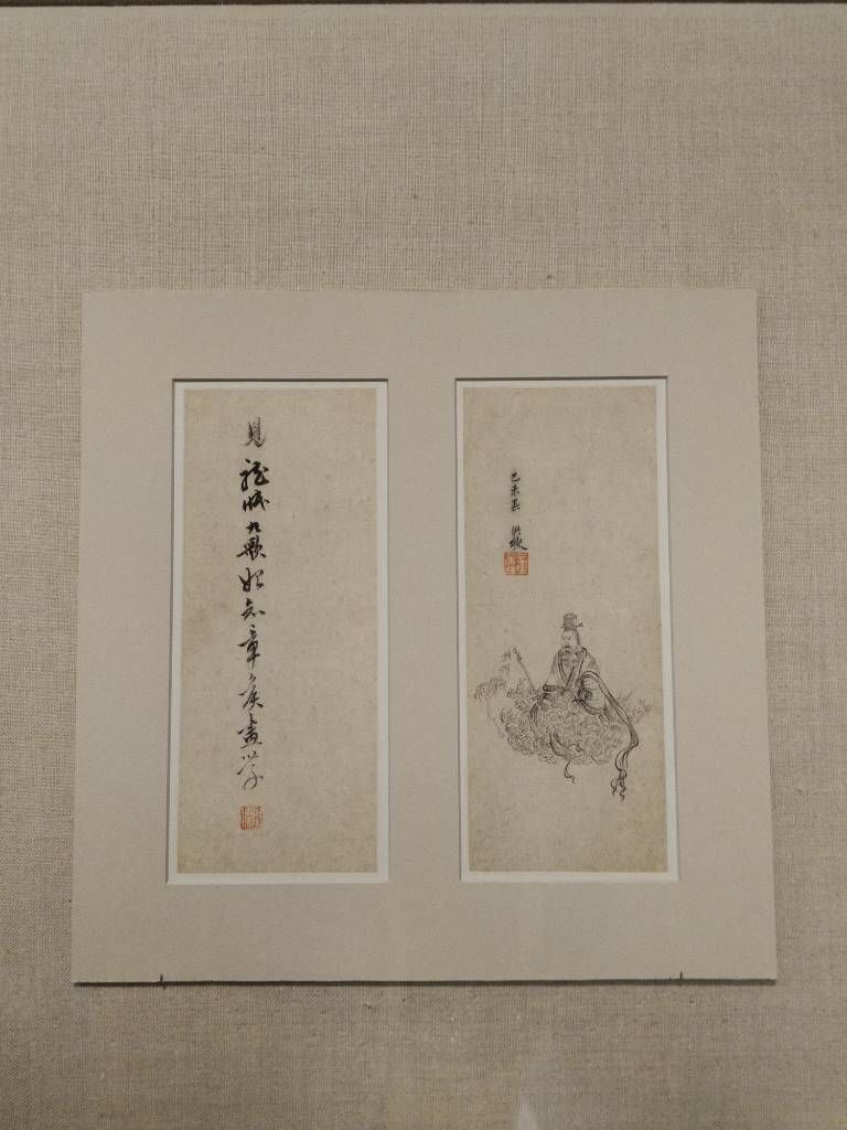Deux petits panneaux, l'un avec une ligne – verticale – de calligraphie et l'autre avec un dessin d'un homme assis dans un paysage